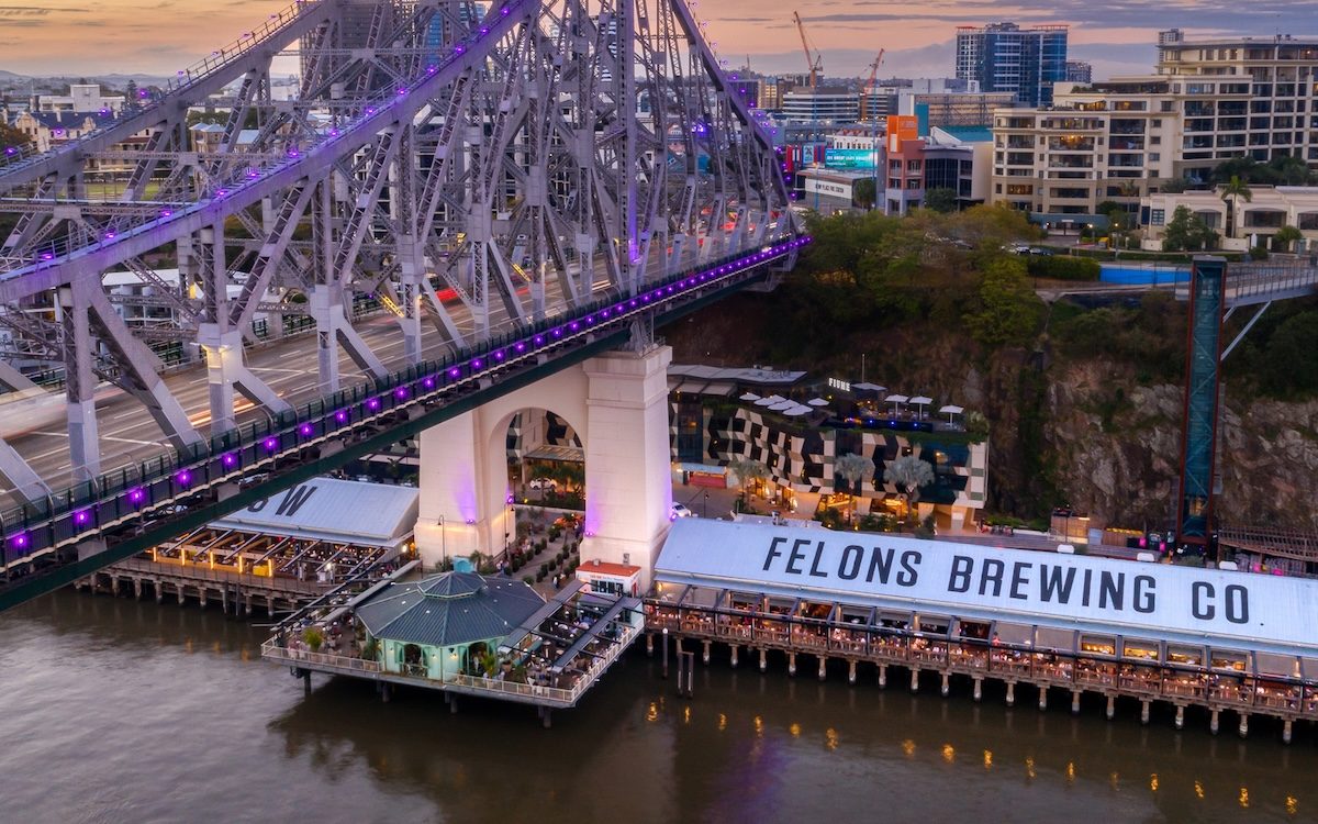 Riverside venue precinct under a city bridge at dusk